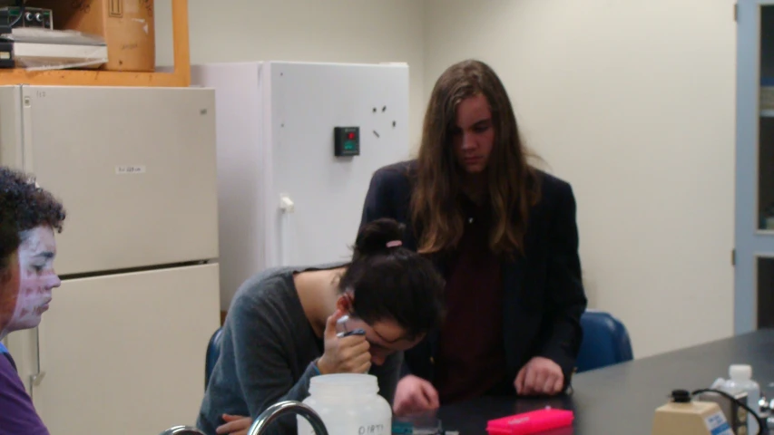 three people in a kitchen and one on the floor