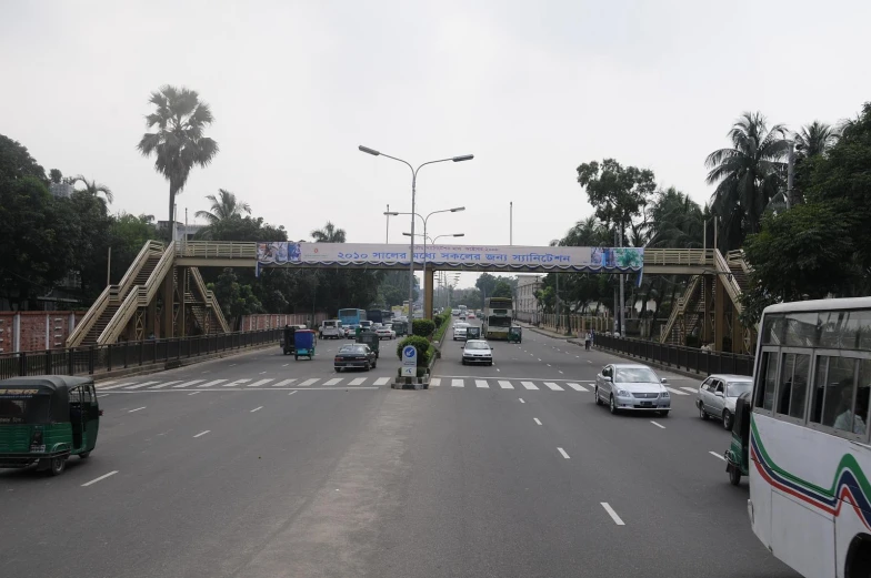 cars and buses drive on a bridge with a walkway above