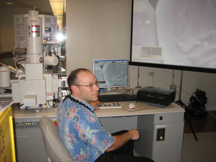 a man sitting in front of a monitor with a mri on the wall