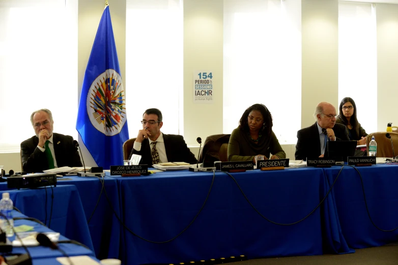 several people sitting at a table with microphones and papers