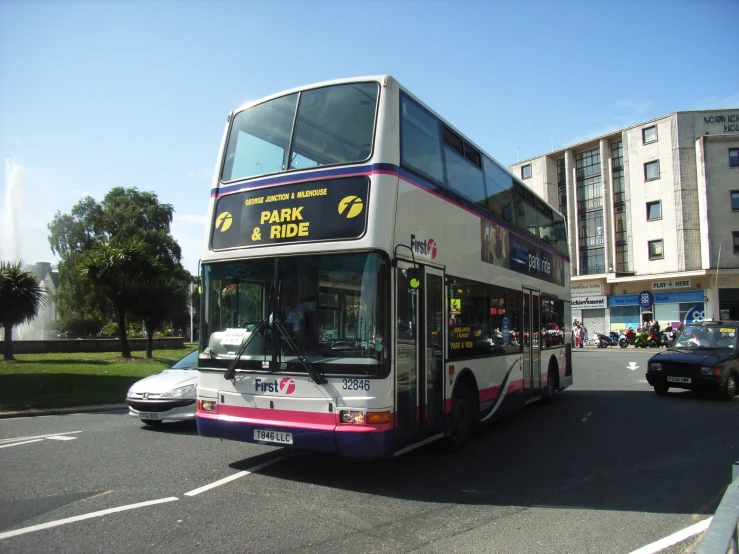 the double decker bus is driving down the street