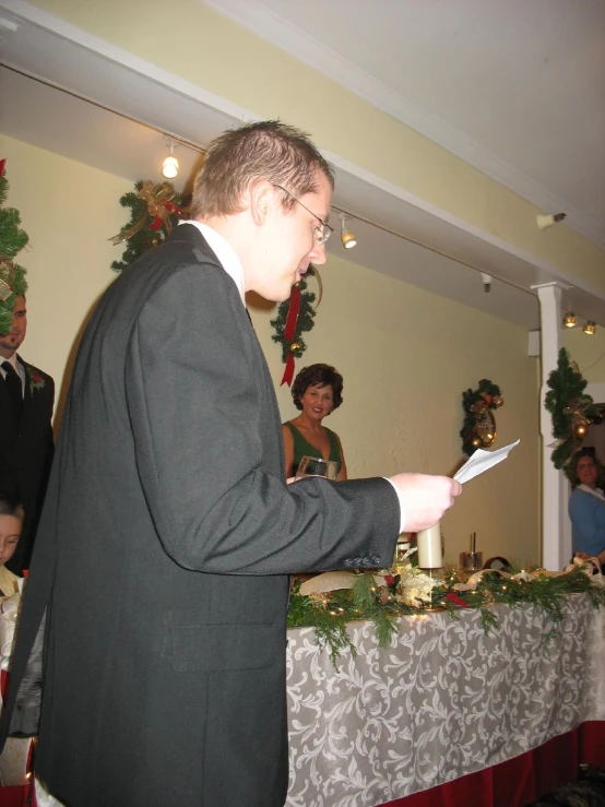 a man in a suit handing soing to someone at a table