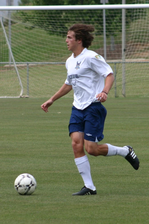 a man with long hair playing soccer in a grassy field