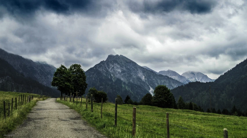 a field with mountains in the background and a trail leading up to it