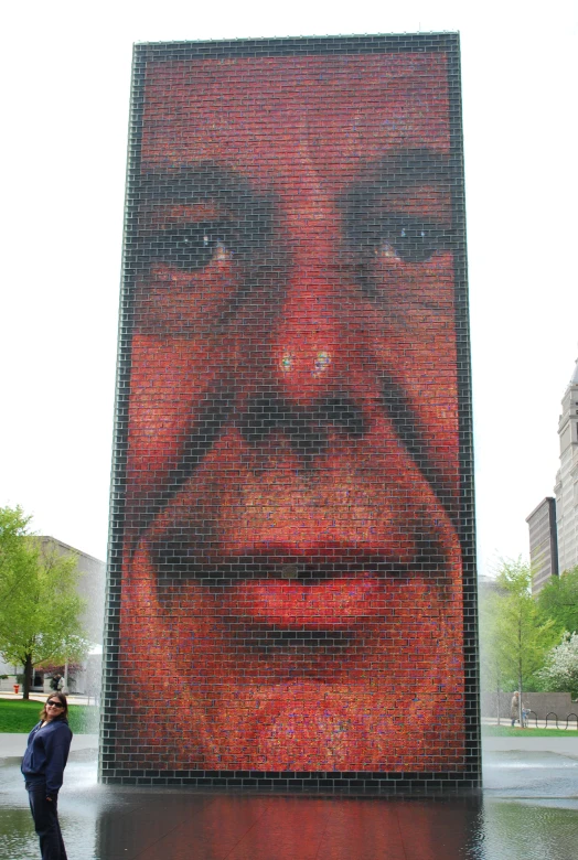 a giant, face made of bricks, on a building next to water