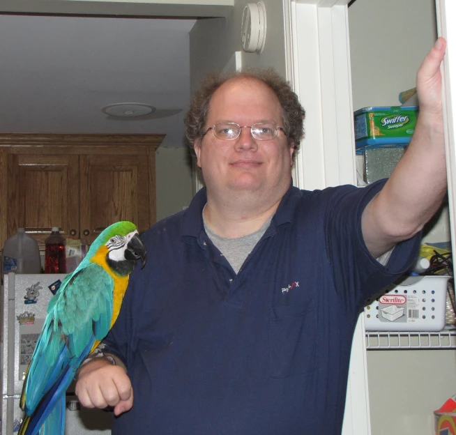 man with big blue shirt and glasses holding a bird