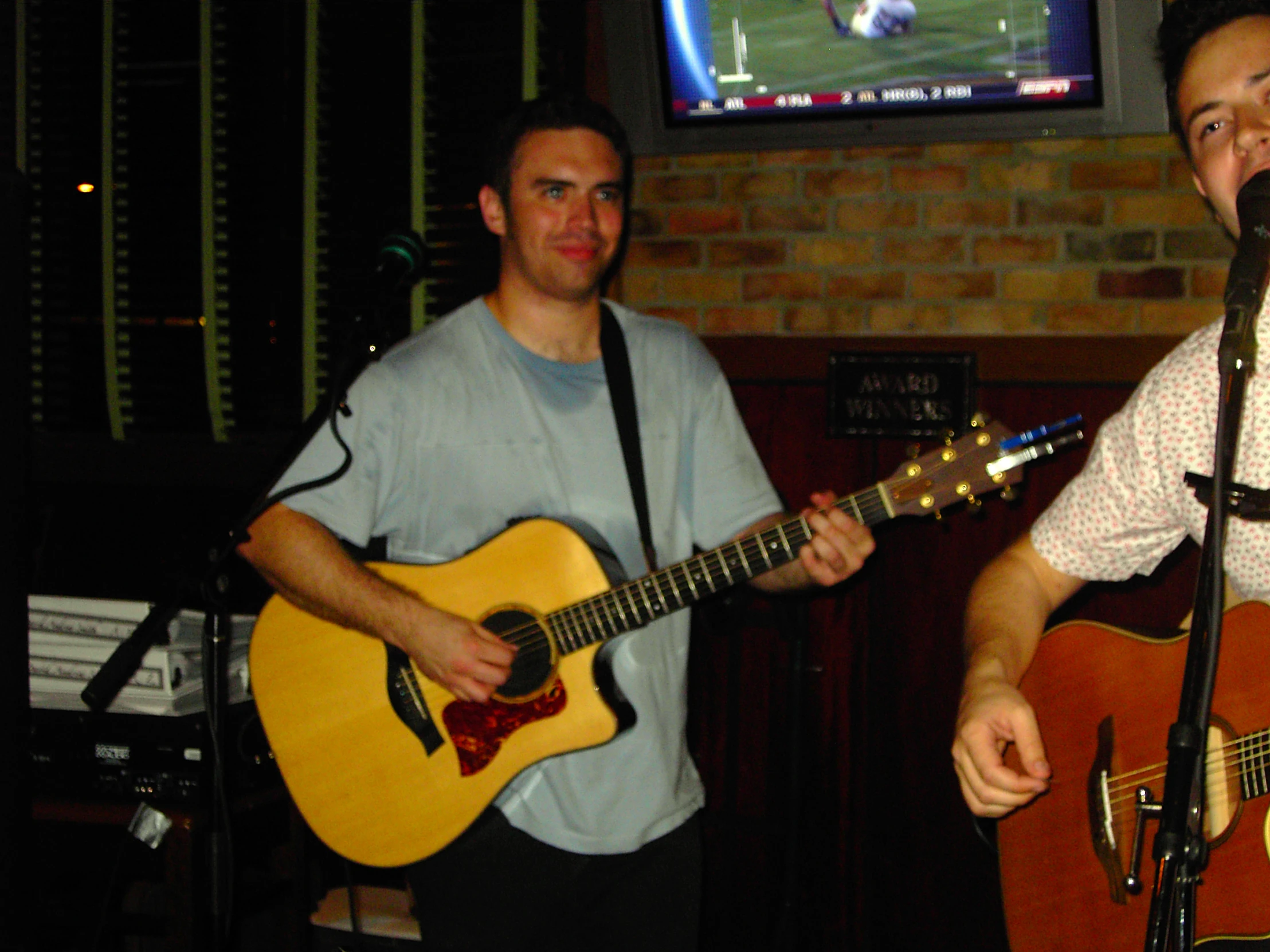 two guys singing together and playing guitars