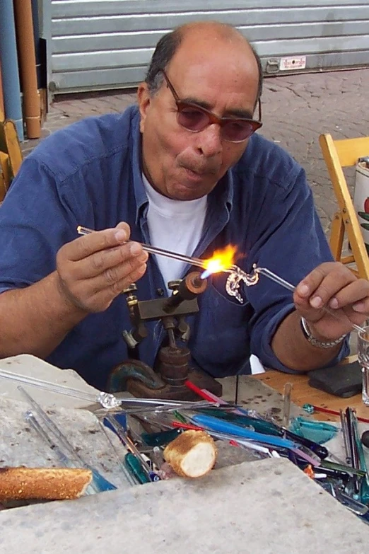 the man is using a lighter to melt the cake into pieces