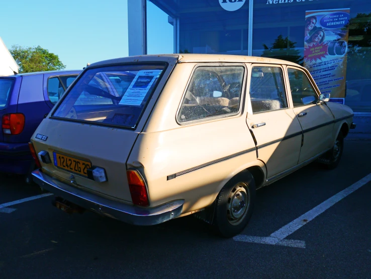 an old yellow car that is parked in a lot