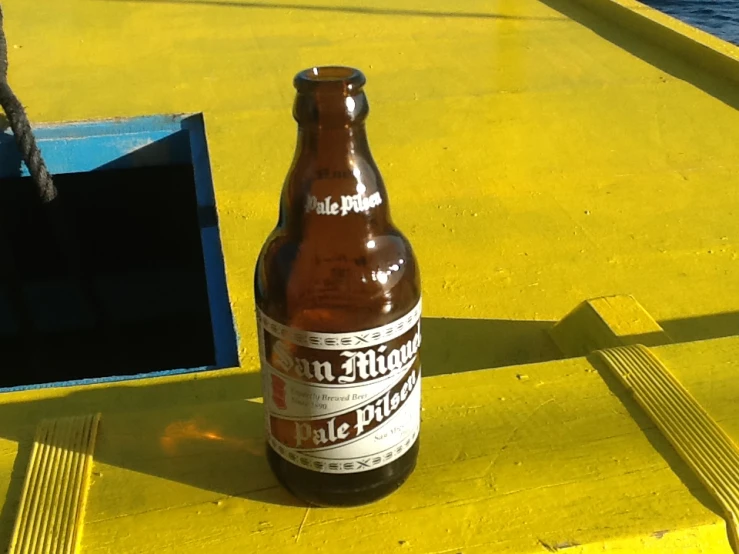 an empty beer bottle sitting on top of a yellow boat