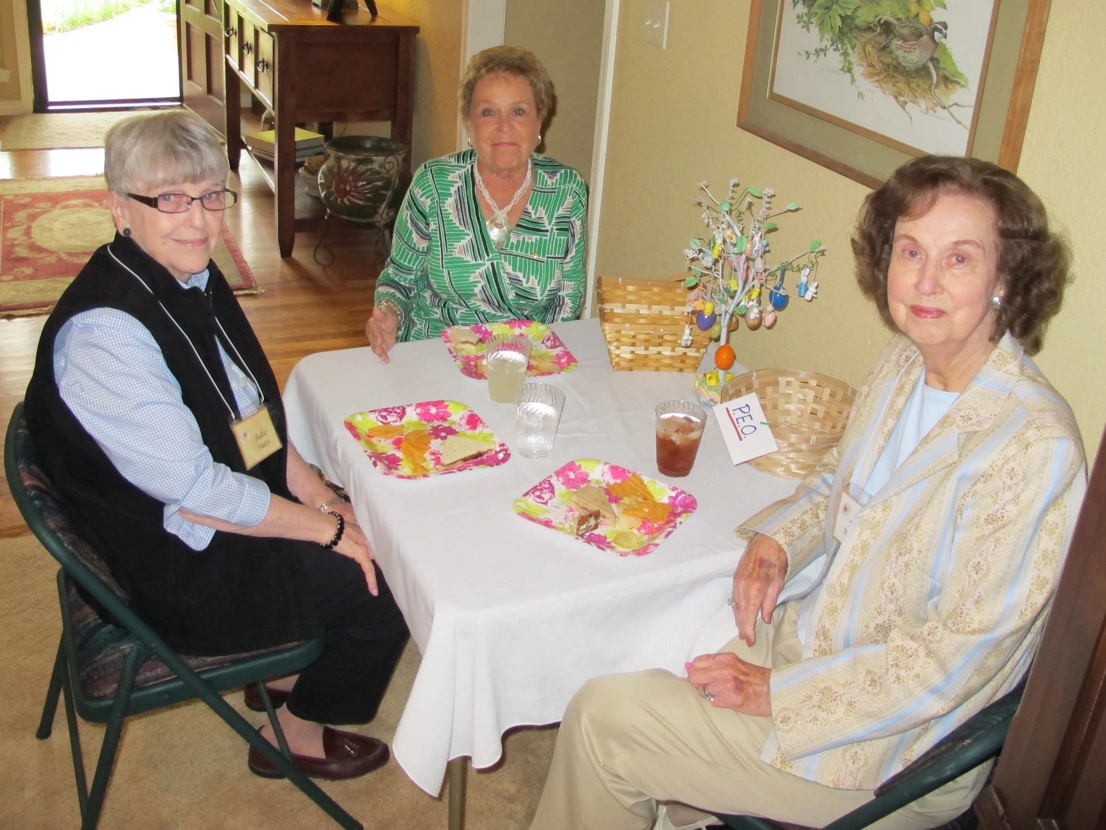 two women and one man sitting at the table in a house