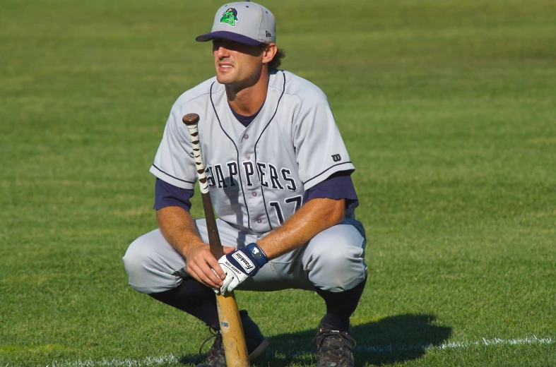 a man in grey uniform holding a baseball bat on the field