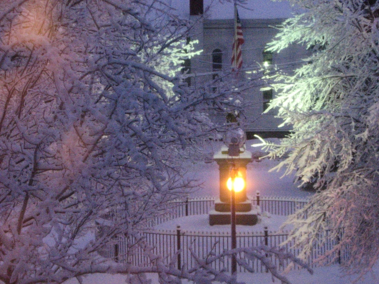 a lamp is lit by an outdoor light in the middle of snowy street