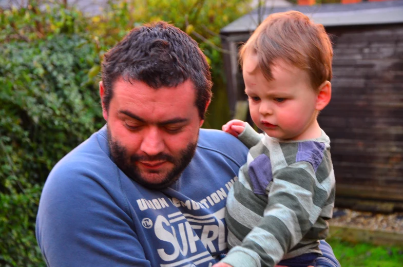 a man holds his child in his arms outside