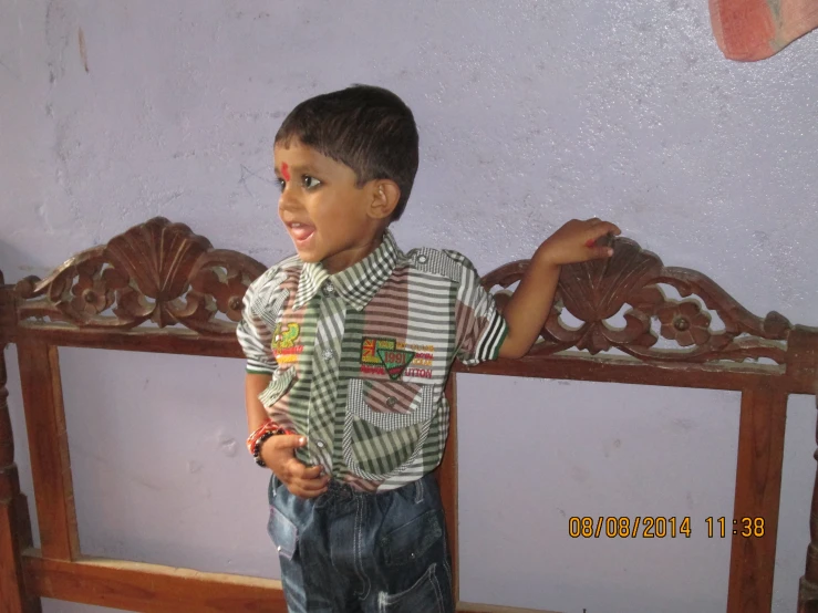 a little boy standing on a bed looking at the camera