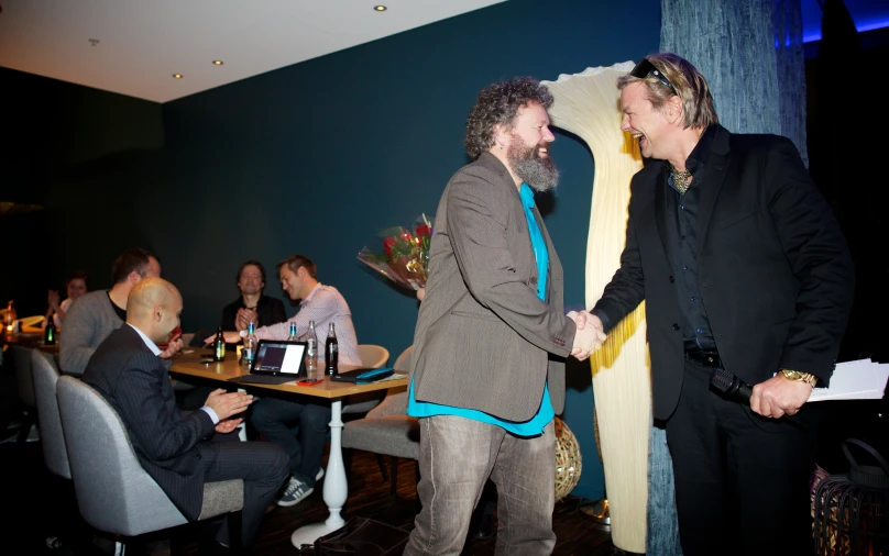 two men shaking hands with each other at a table