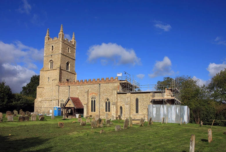 a old brick church with a steeple, surrounded by green cemetery graves