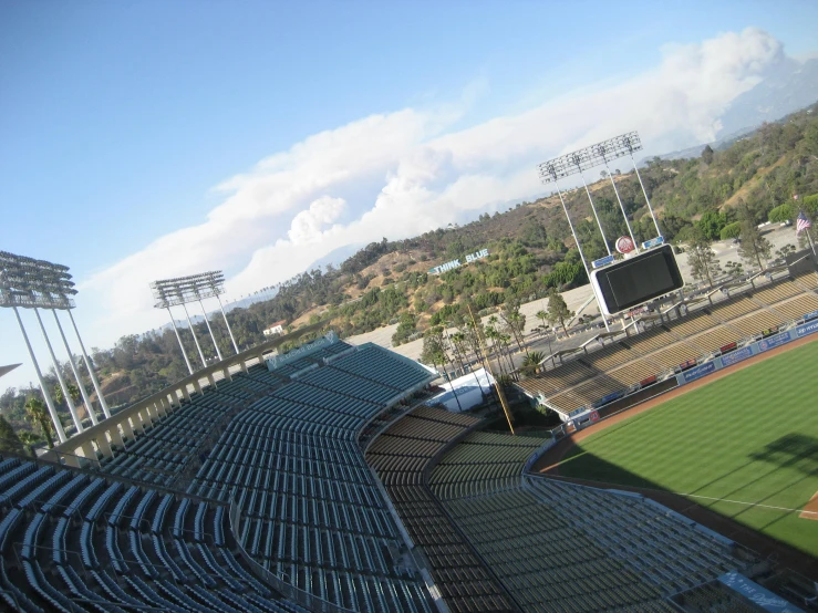 an empty baseball stadium with green grass and mountain in background