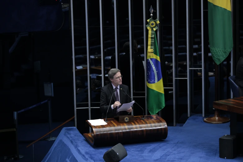 a man sitting at a podium reading soing