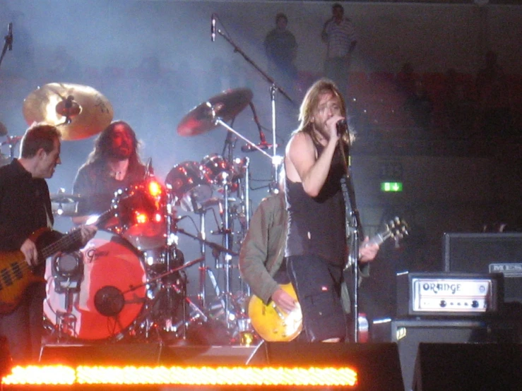 a man standing on a stage playing a guitar and microphone