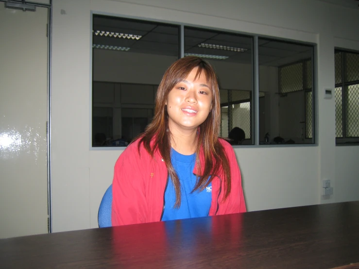 a smiling woman with long hair standing in front of a wooden desk