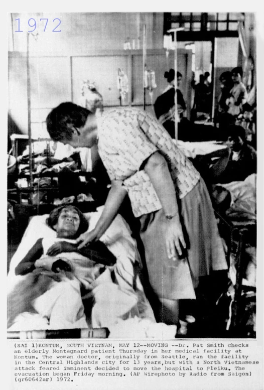 a woman in an apron getting help from a man in a hospital bed