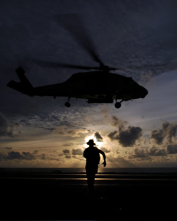 a person standing in front of a helicopter at sunset