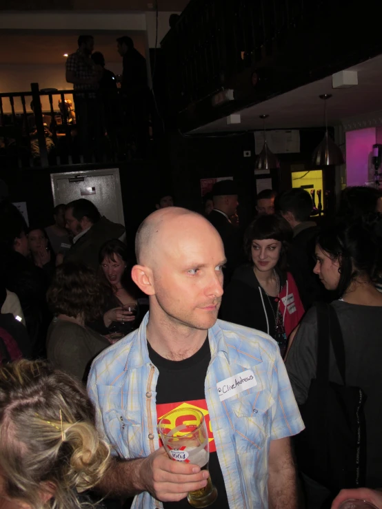 a bald man holding a beer at a party