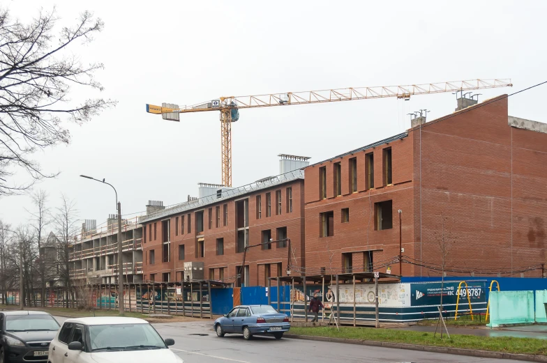 cars are parked outside a brown brick building with a crane on top