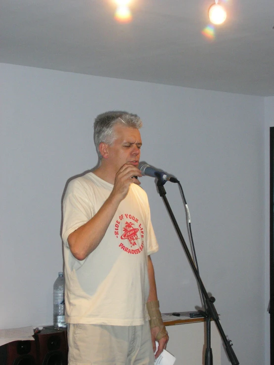 a man holding a microphone up to his ear in front of a microphone stand