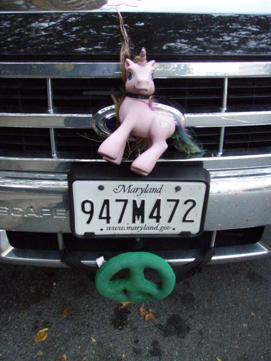 pink pony sitting on the front grill of a car