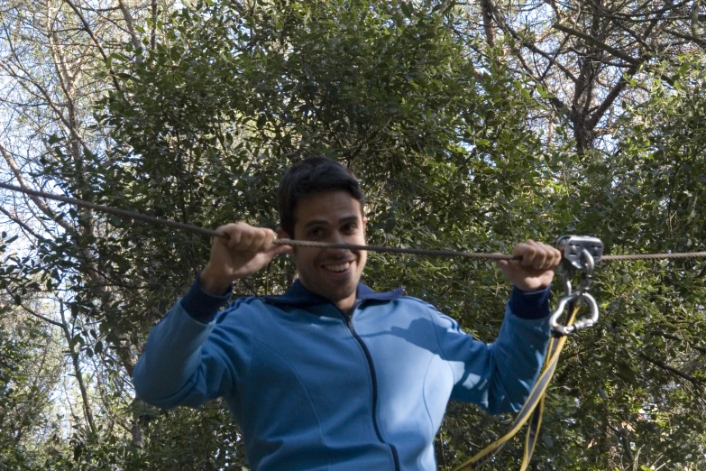 man holding two strings above his head in the woods