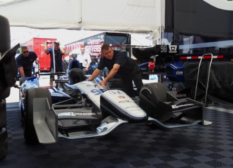 a man painting a racing car with another man standing next to it