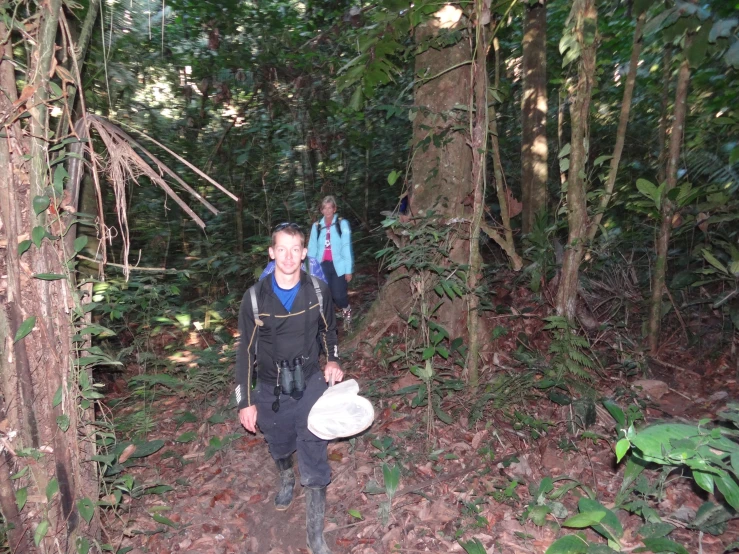 man standing on path with white object in wooded area