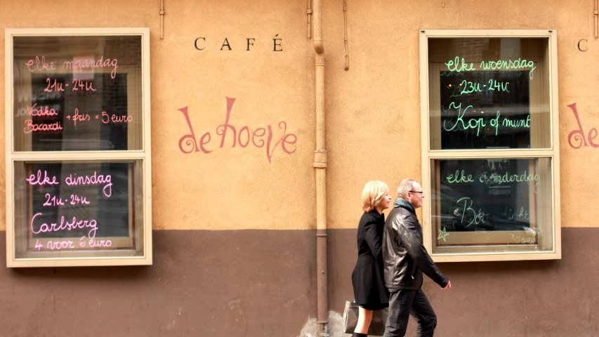 two people are walking in front of a cafe