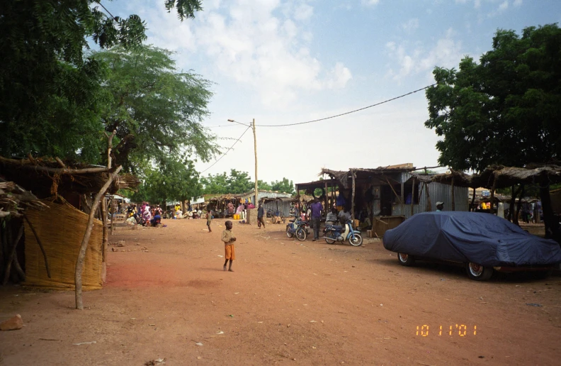 a little boy walking across a dirt road