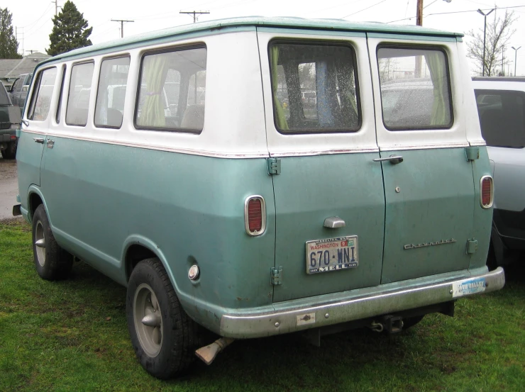 a green and white minivan sitting in the grass
