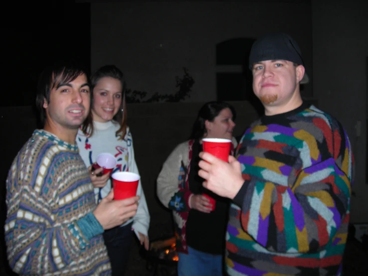 four young people standing outside holding up cups