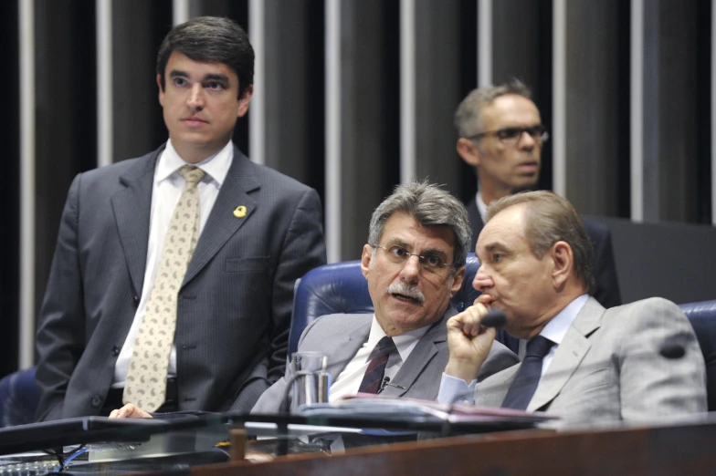 a number of men sitting in front of microphones