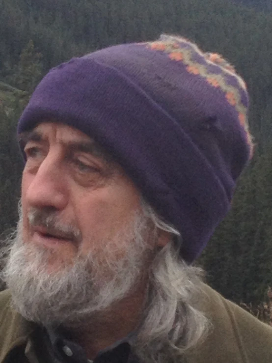 an old man with grey hair and a purple hat looking to the left