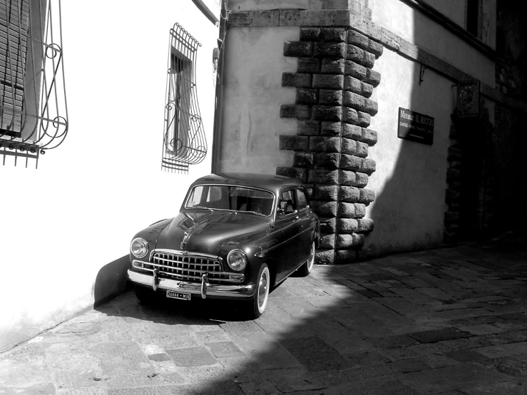 an old black car parked outside of a building