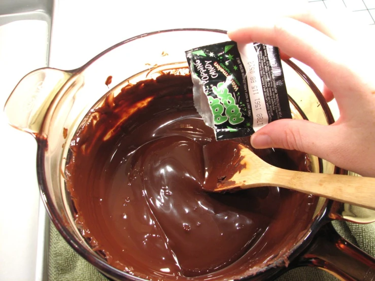a person mixing chocolate in a bowl with a spoon