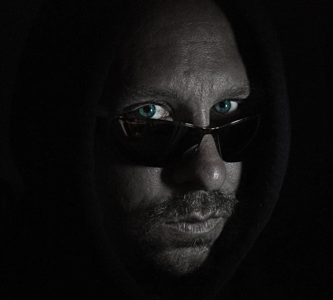 a man with blue eyes wearing sunglasses in the dark
