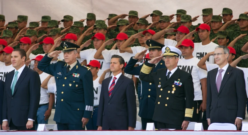 two military officers salute as men watch in uniforms