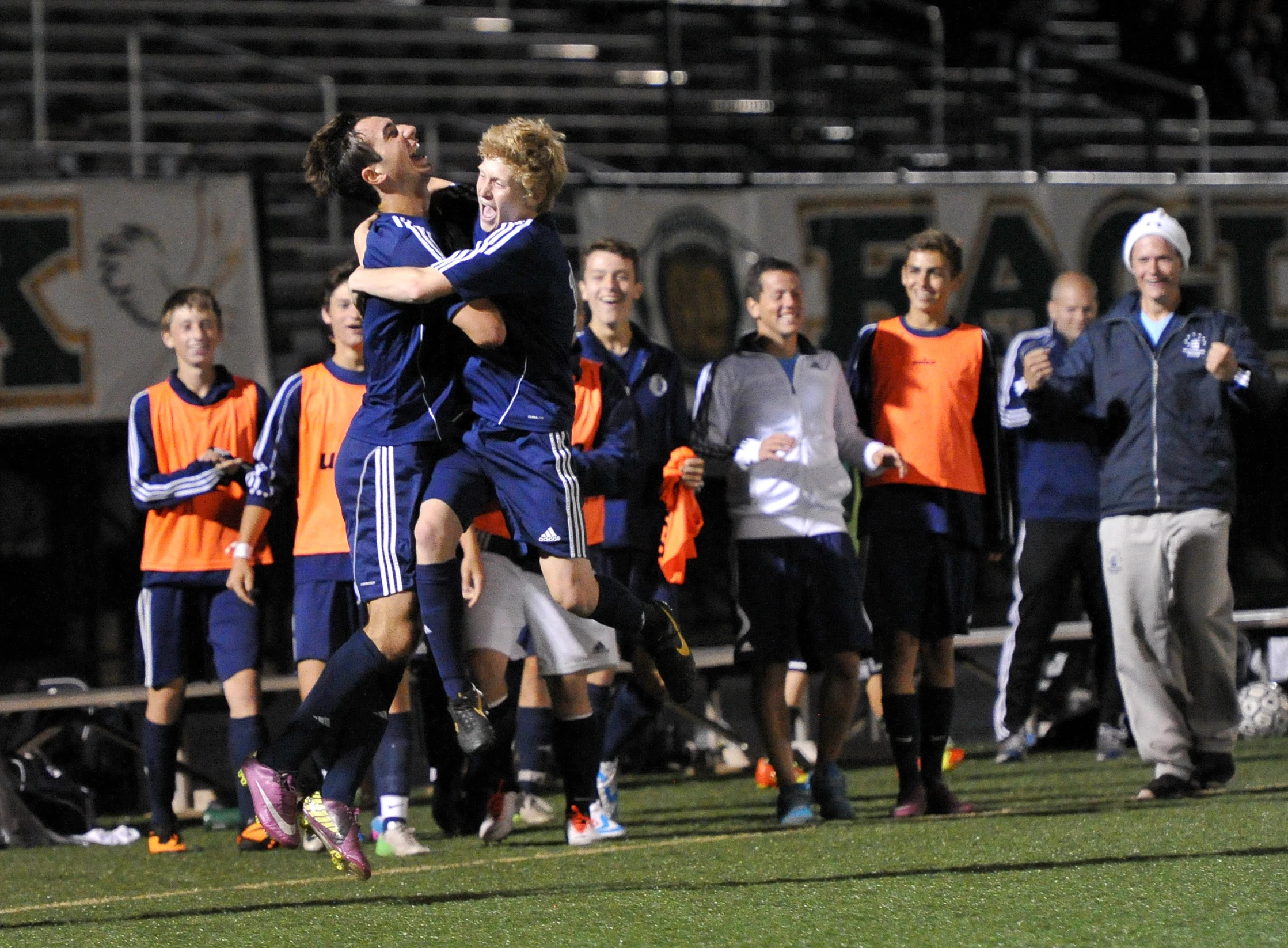 two men on soccer field one has his arms around the other