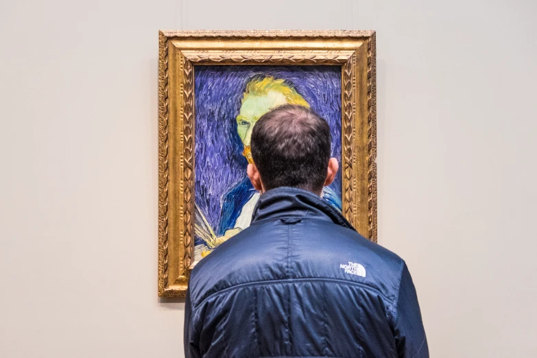 a man looking at a painting with blue paint