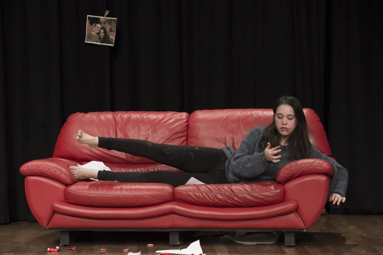 a woman laying on top of a red couch