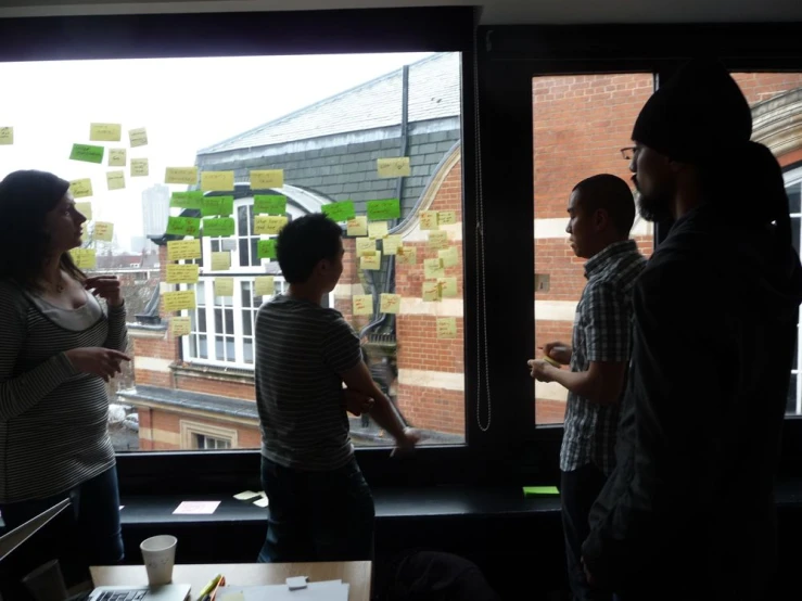 a group of young men and women are standing near the window