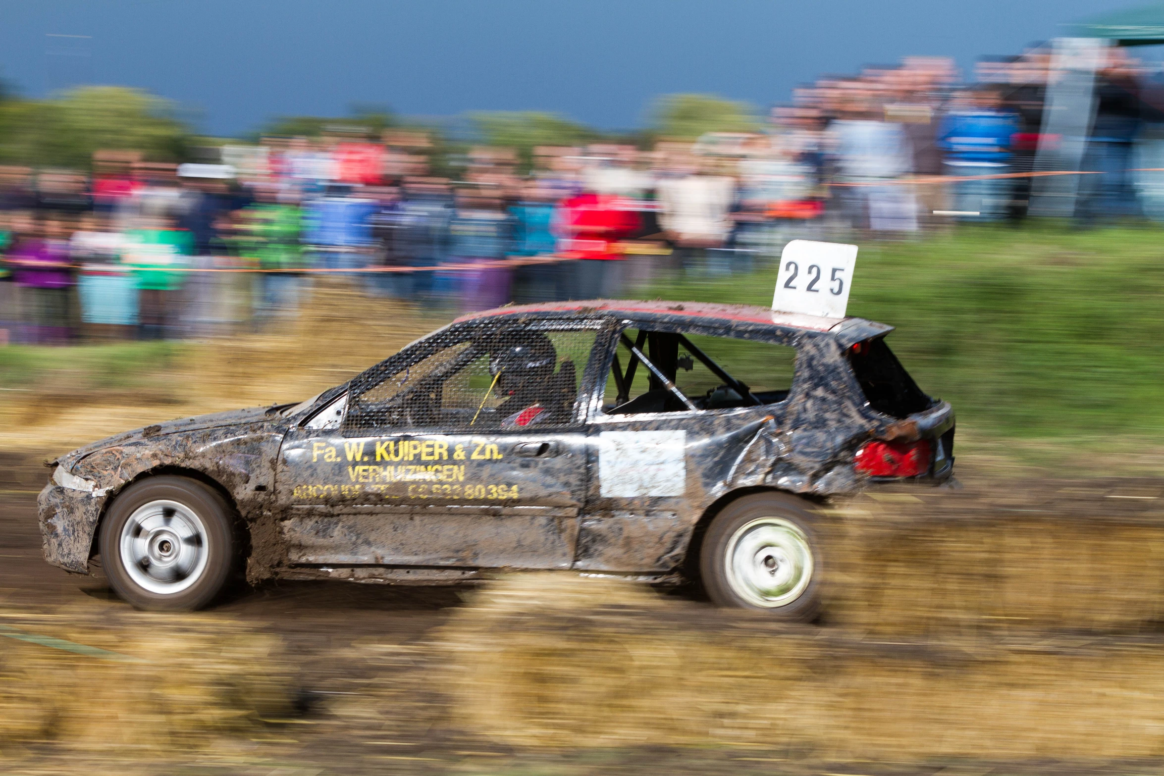 a car racing in a dirt field with a banner on top