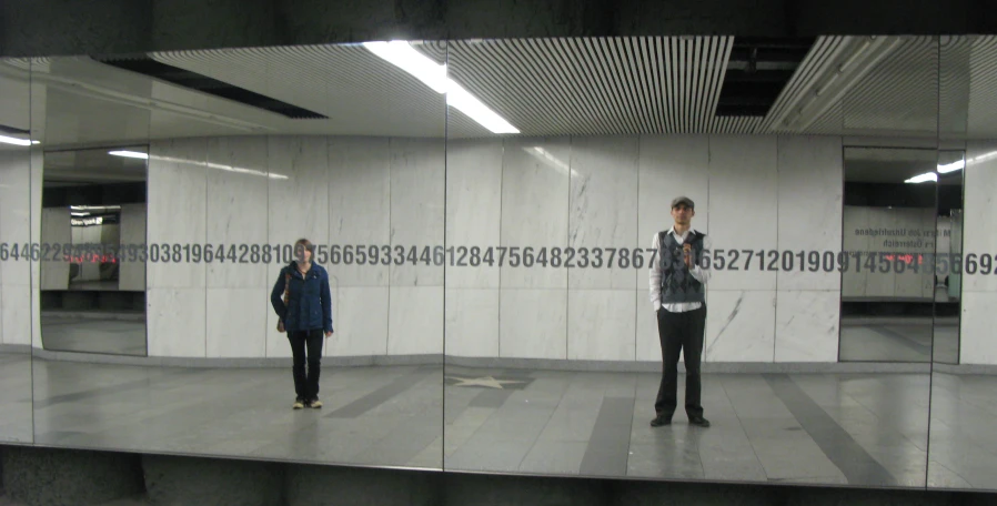 a woman stands in front of a mirror with a man taking a picture